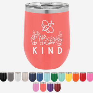 May include: A coral pink stainless steel wine tumbler with a white bee and the word "KIND" in sign language. The tumbler is shown with a variety of color options.