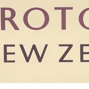May include: A vintage sign with the text "Rotorua New Zealand" in a brown font on a light beige background.