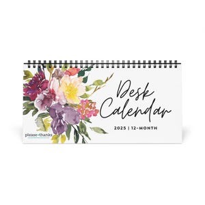 May include: A white desk calendar with a floral design featuring watercolor purple, pink, yellow, and green flowers. The text "Desk Calendar 2025 | 12-Month" is printed on the calendar.
