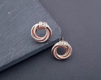 Puede incluir: Un par de pendientes de alambre de oro rosa con un diseño de círculo anudado.