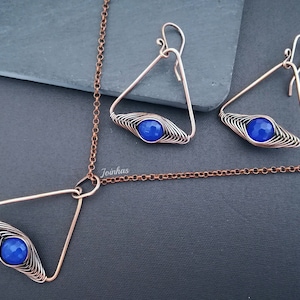 May include: A copper necklace and earrings set with a blue gemstone in a triangular wire frame.