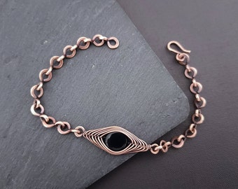 May include: A copper chain bracelet with a black gemstone set in a copper wire design.