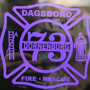 May include: Purple and black fire department emblem with the text "Dagsboro" and "Dornienburg" and the number "73" in the center. The emblem also includes a ladder, a fire hydrant, and the words "Fire Rescue".