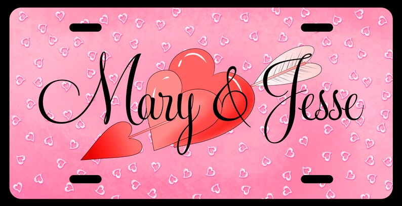 May include: A pink license plate with a pattern of small white hearts. The plate features two red hearts pierced by an arrow, with the names "Mary & Jesse" in elegant script.