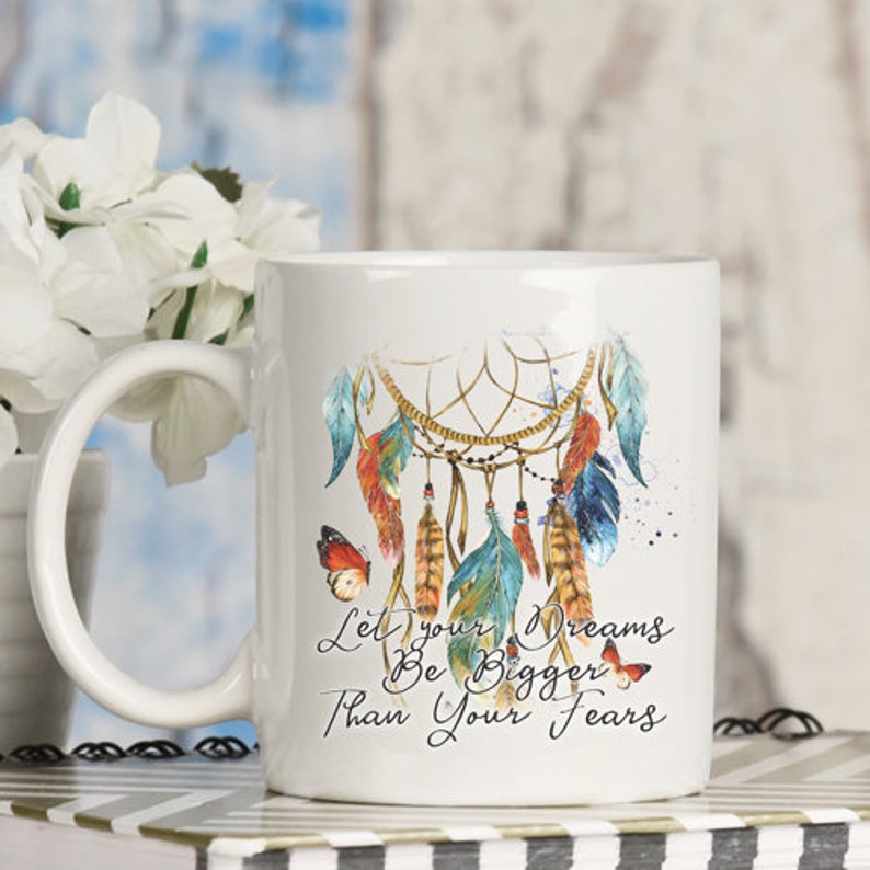 May include: White ceramic mug with a dreamcatcher design and the text "Let your dreams be bigger than your fears". The dreamcatcher is decorated with feathers and butterflies.