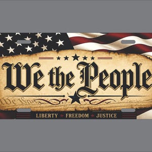 May include: A rectangular license plate featuring a waving American flag background. The center displays a parchment-style graphic with the black text We the People, a central star, and the words Liberty, Freedom, and Justice at the bottom.