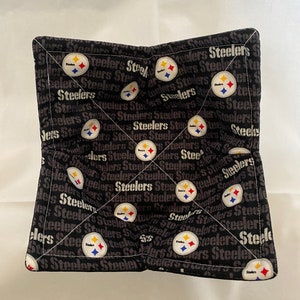 May include: Black and white pot holder with the Pittsburgh Steelers logo and the word "Steelers" repeated throughout the design.