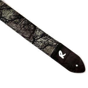 May include: Black guitar strap with a white 'R' logo and a black and white tree pattern.