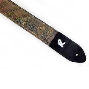 May include: A black guitar strap with a gold iridescent fabric and a white "R" logo.