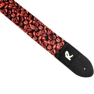 May include: A black guitar strap with a coffee bean pattern and a white "R" logo.