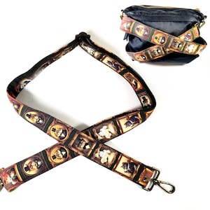 May include: A black adjustable shoulder strap with a gold metal clasp. The strap is decorated with a repeating pattern of framed images of cats wearing hats and bow ties.