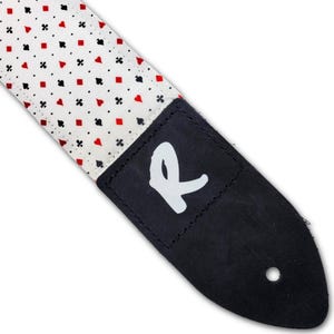 May include: A guitar strap with a white background and a pattern of red and black playing card symbols. The strap has a black leather end with a white "R" logo.