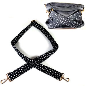 May include: Black and white paw print patterned adjustable shoulder strap with gold hardware. The strap is shown on a black bag.