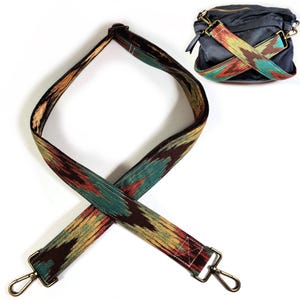 May include: A patterned bag strap with gold-coloured metal clasps. The strap has a design in shades of brown, teal, and yellow. A dark blue bag with a matching strap is also shown.