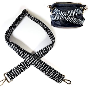 May include: Black crossbody bag with a matching strap. The strap is black with a white moon phase pattern. The bag has a gold zipper and gold hardware. The strap is 101.6 cm long.
