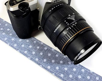 May include: A silver Pentax ZX-30 camera with a black lens. The camera is sitting on a blue and white polka dot fabric strap.