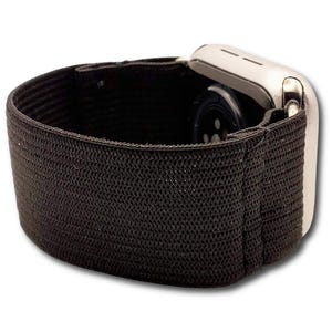 May include: A black elastic watch band is shown, attached to a silver smartwatch. The band is made of a woven material and appears to be stretchy. The watch face is visible, showing the sensors on the back.