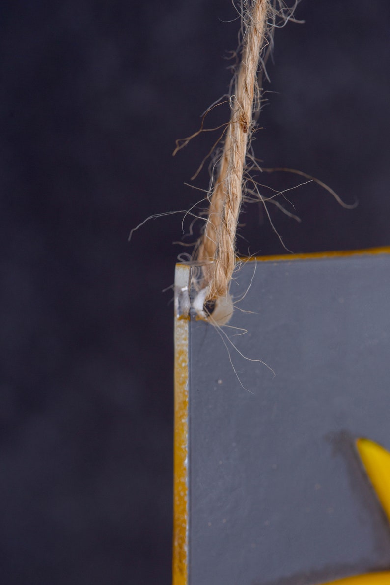 Puede incluir: Primer plano de una pizarra gris con borde amarillo. Un trozo de cuerda est&aacute; atado a la parte superior de la pizarra.