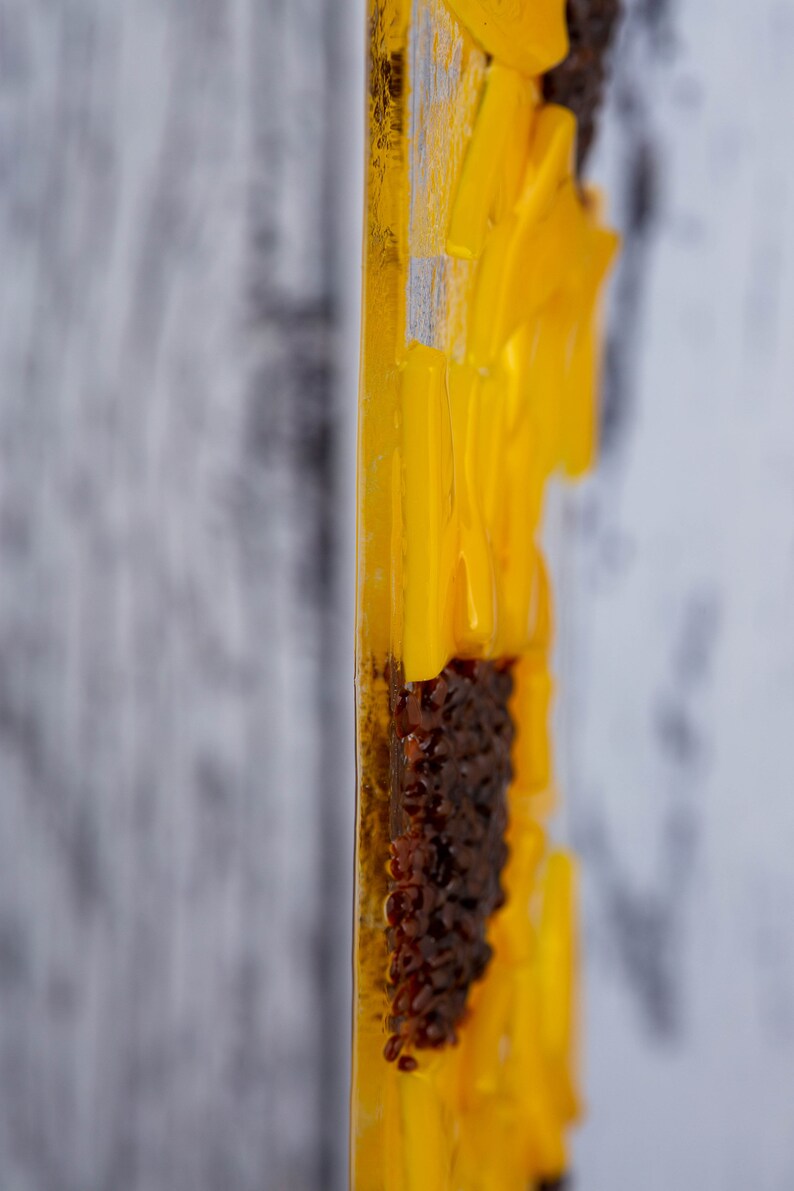 Puede incluir: Primer plano de una pieza de arte de resina amarilla y marr&oacute;n. La pieza est&aacute; hecha de m&uacute;ltiples capas de resina, con una superficie texturizada. La pieza tiene forma de flor, con un centro marr&oacute;n y p&eacute;talos amarillos.