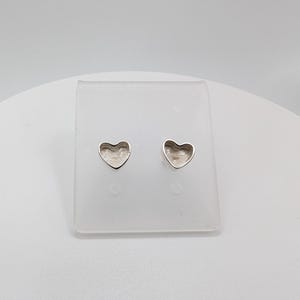 May include: A pair of silver heart-shaped stud earrings. The earrings are displayed on a clear plastic stand against a white background. The heart shapes have a slightly textured surface.
