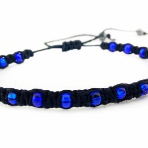 May include: A black cord bracelet with blue glass beads.