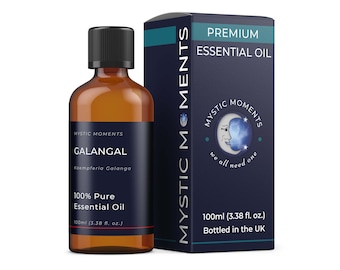 Könnte beinhalten: Eine braune Glasflasche mit schwarzem Verschluss, die 100 % reines Galangal-Ätherisches Öl enthält. Die Flasche ist mit "Mystic Moments Galangal Kaempferia Galanga 100% Pure Essential Oil 100ml (3.38 fl. oz.)" beschriftet. Die Flasche steht neben einer blauen Box mit dem Text "Mystic Moments Premium Essential Oil" und einer Mondgrafik.