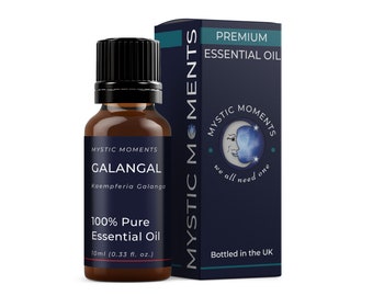 Könnte beinhalten: Eine braune Glasflasche mit schwarzem Verschluss, die 100 % reines Galangal-Ätherisches Öl enthält. Die Flasche ist mit "Mystic Moments Galangal Kaempferia Galanga 100% Pure Essential Oil 10ml (0.33 fl. oz.)" beschriftet. Die Flasche steht vor einer blau-weißen Schachtel mit dem Text "Mystic Moments Premium Essential Oil" und einem Mond- und Sternenmotiv.
