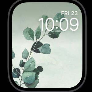 May include: A digital clock face with a white background and green foliage. The time is 10:09 and the day is Friday the 23rd.