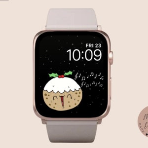 May include: A digital watch face with a black background and a cartoon illustration of a Christmas pudding singing with musical notes. The time is 10:09 and the date is FRI 23. The watch face is on a rose gold Apple Watch with a light gray band.