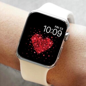 May include: White Apple Watch with a black face displaying the time 10:09 and the date FRI 23. The watch face has a red heart made of smaller red hearts.