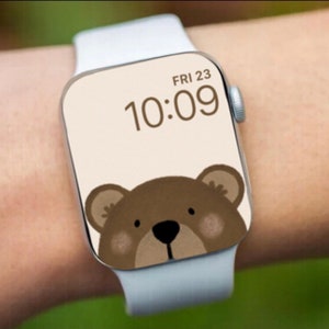 May include: A white Apple Watch with a brown bear face watch face. The time is 10:09 and the date is FRI 23.