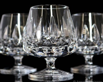 Puede incluir: Tres copas de brandy de cristal transparente con un diseño de cristal tallado. Las copas están dispuestas en fila sobre un fondo negro.