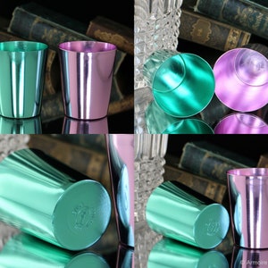 K&ouml;nnte beinhalten: Vier vintage Metall-Schnapsgl&auml;ser, zwei gr&uuml;n und zwei rosa, mit gl&auml;nzendem Metallic-Finish. Die Gl&auml;ser sind paarweise angeordnet, ein Paar auf dem Kopf stehend und das andere Paar aufrecht.