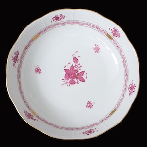 Op de afbeelding: Een witte porseleinen kom met een roze bloemenmotief en een gouden rand. De kom heeft een gegolfde rand en een geweven patroon.