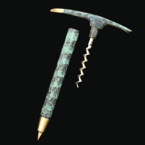 May include: A green and gold metal corkscrew with a long, thin handle and a spiral corkscrew. The corkscrew is separated into two pieces.