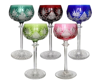 May include: Set of five crystal wine glasses with cut glass designs. The glasses are in various colors: green, red, blue, pink, and clear.
