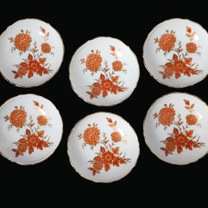 May include: Set of six white porcelain dessert plates with a gold rim and a floral design in shades of orange and gold.