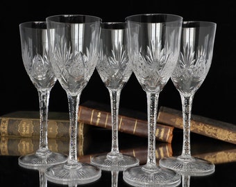 May include: Set of six clear crystal wine glasses with a cut glass design. The glasses have a tall, slender stem and a round bowl.