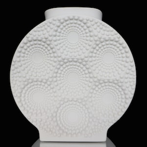 Może przedstawiać: Biały ceramiczny wazon o okrągłym, fakturowanym wzorze. Wazon ma wypukły wzór z kółek i kropek.