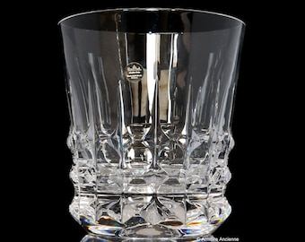 May include: A clear glass tumbler with a cut crystal design. The glass has a wide base and a straight, cylindrical body. The bottom of the glass has a starburst pattern.