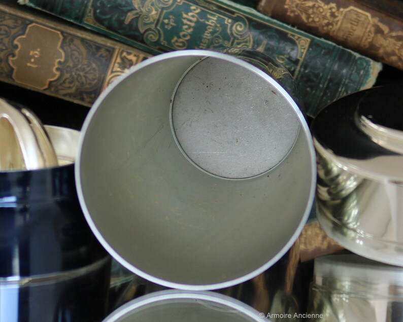 K&ouml;nnte beinhalten: Ein silberner Cocktail-Shaker aus Metall mit einer glatten, gl&auml;nzenden Oberfl&auml;che. Der Shaker ist offen und das Innere ist sichtbar.