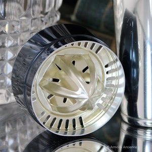K&ouml;nnte beinhalten: Nahaufnahme eines silbernen Cocktailshakers mit schwarzem Deckel und einem eingebauten Zitruspresse. Die Presse hat eine sternf&ouml;rmige Form mit L&ouml;chern zum Auspressen von Zitrusfr&uuml;chten.