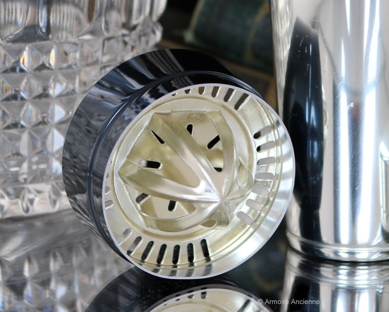 K&ouml;nnte beinhalten: Nahaufnahme eines silbernen Cocktailshakers mit schwarzem Deckel und einem eingebauten Zitruspresse. Die Presse hat eine sternf&ouml;rmige Form mit L&ouml;chern zum Auspressen von Zitrusfr&uuml;chten.