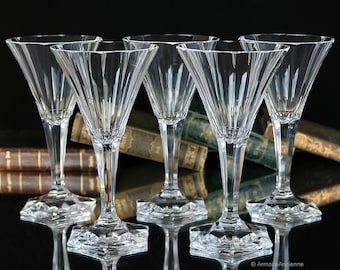 May include: Set of five clear glass martini glasses with a fluted design and a square base. The glasses are arranged in a row on a black surface.