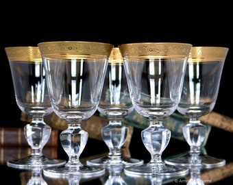 May include: Set of five clear glass wine glasses with gold trim around the top. The glasses have a short stem and a round bowl.