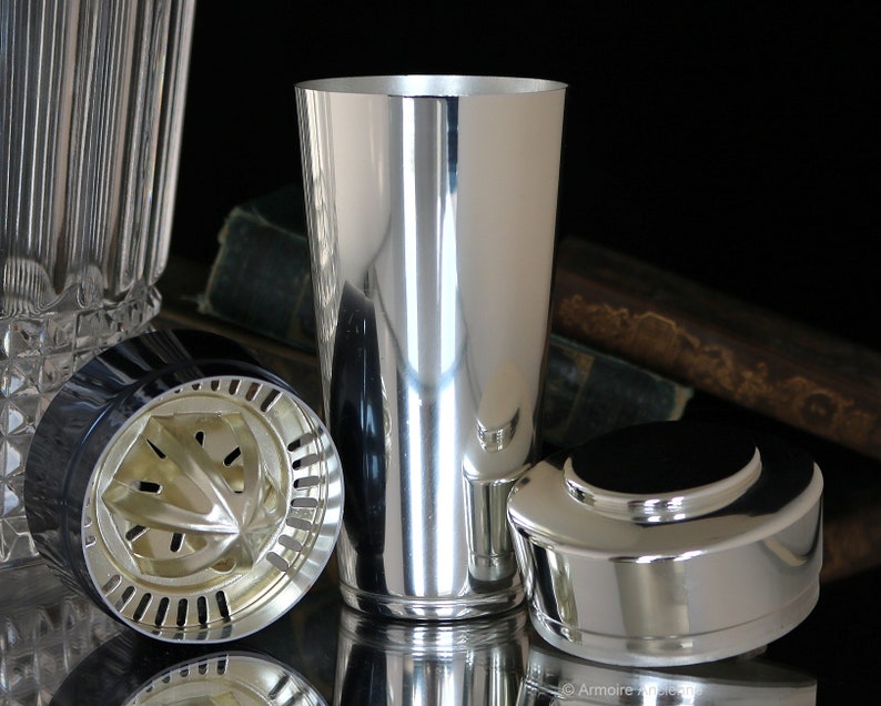 K&ouml;nnte beinhalten: Ein silberner Cocktailshaker mit einem Sieb und einem Deckel. Der Shaker ist aus Metall und hat eine gl&auml;nzende Oberfl&auml;che.