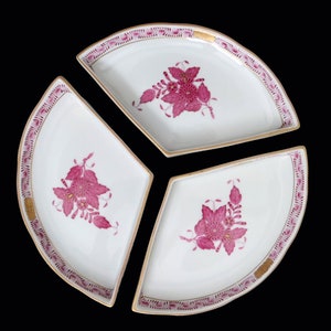 May include: Three white porcelain serving dishes with pink floral designs and gold trim. The dishes are shaped like pie slices and fit together to form a circle.