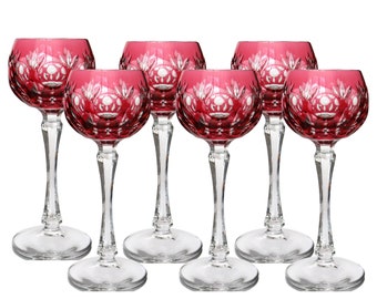 May include: Set of six red crystal wine glasses with a cut glass design. The glasses have a round bowl and a long, slender stem.