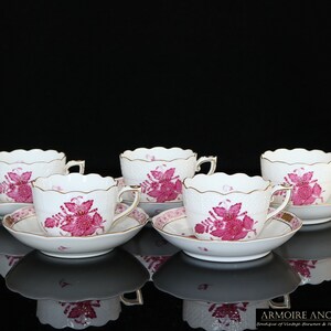 Puede incluir: Juego de cuatro tazas de té y platillos de porcelana rosa y blanca con un diseño floral. Las tazas y los platillos tienen un borde festoneado y están decorados con un delicado patrón floral rosa.