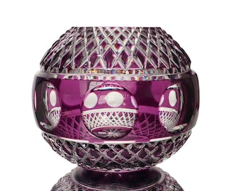 May include: A purple glass vase with a geometric pattern and a round shape. The vase has a clear glass base and a decorative design.